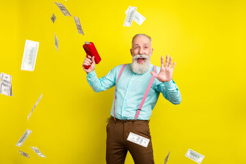 Photo of funky old man play money gun wear blue shirt isolated on yellow color background