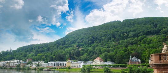 The city at the foot of the mountain on the river bank. Wide photo.