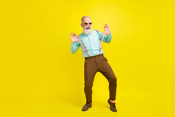 Full length body size photo elder man wearing suspenders sunglass relaxing on holidays laughing isolated bright yellow color background
