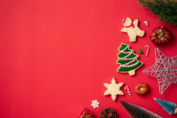 Decorated Christmas gingerbread cookies with decorations on red table background.