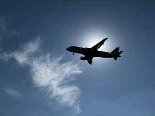 Fototapeta na wymiar An airplane covering the sun against a blue sky
