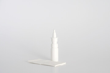 White plastic nasal spray bottle on white background. Nasal spray container, saline water solution for nose congestion treatment. Runny nose, colds. Free space, copy space.