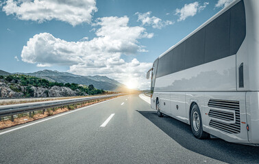 White passenger bus on the highway against the backdrop of a beautiful landscape. - obrazy, fototapety, plakaty