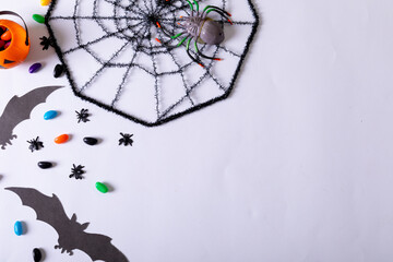 Composition of halloween decorations with spider web, bats and sweets with copy space on white