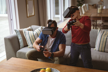 Caucasian father and son wearing vr headsets playing video games at home