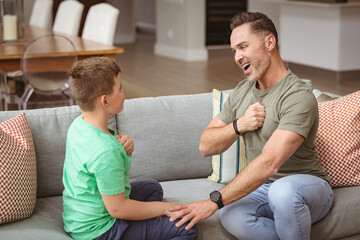 Caucasian father and son communicating using sign language while sitting on the couch at home