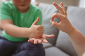 Two caucasian boys communicating using sign language while sitting on the couch at home