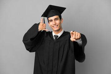 Young Argentinian university graduate isolated on grey background making phone gesture and pointing front