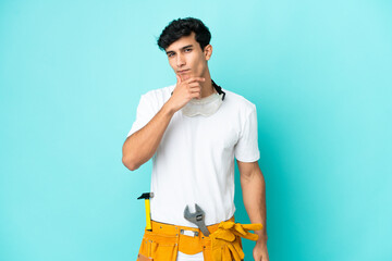 Young electrician Argentinian man isolated on blue background thinking