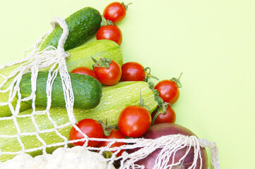 Ripe juicy red tomatoes, green cucumbers and zucchini in a string bag.