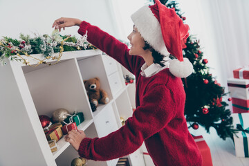 Photo of curious funny little boy investigate x-mas decorations wear jumper hat in decorated home indoors