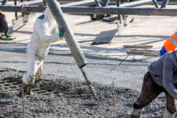 Pouring and smoothing out concrete with ready-mix concrete (RMC) in the construction site. It is...