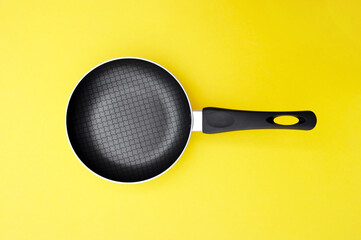 A non-stick skillet on a bright yellow background.