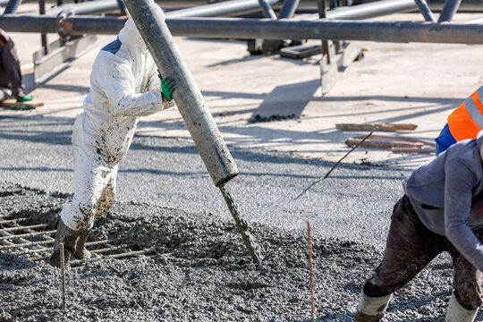 Pouring and smoothing out concrete with ready-mix concrete (RMC) in the construction site. It is concrete that is manufactured in a batch plant, according to a set engineered mix design.