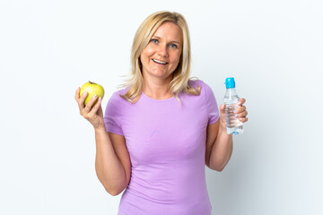 Middle age woman isolated on white background with an apple and with a bottle of water