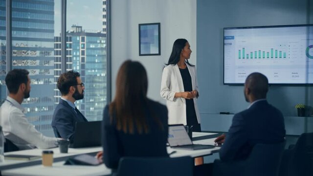 Office Conference Room Meeting: Portrait of Confident Asian Female Top Manager Presents e-Commerce Investment Strategy for Group of Digital Entrepreneurs. Wall TV with Big Data Analysis, Infographics
