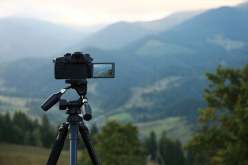 Taking video with modern camera on tripod in mountains