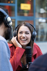 Young woman with microphone and headphones working outside conducting recording interview for tv or...
