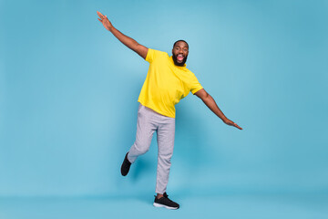 Photo of cute adorable dark skin man wear yellow t-shirt dancing smiling isolated blue color background