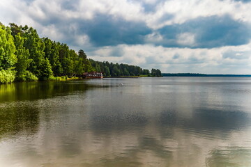 The shore of the pond against the blue sky with white clouds