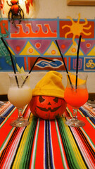Halloween pumpkin in a yellow beanie hat with two Mexican and Cuban cocktails on holiday in rich colors. Vertical photo