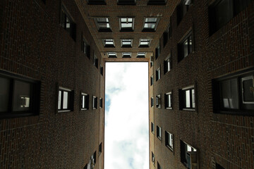  Upward looking perspective of cloudy sky through a framing of residential block in the Bronx, New...