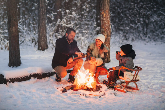 Happy Family Frying Marshmallows Over Fire In Winter