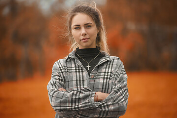 Beautiful girl in the autumn park. With a cross on the chest