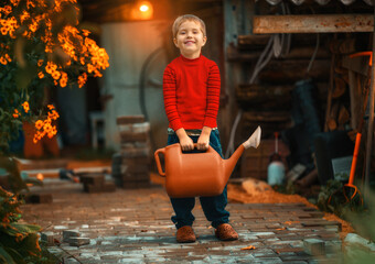 A boy with a watering can in a red jacket smiles