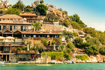 View of a small town on a hillside on which stands the Simena fortress. Turkey, Kekova island. Summer. Boat trip