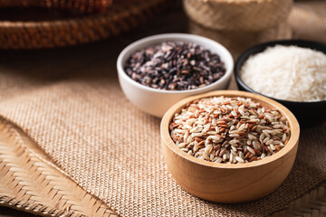 Various Organic Thai rice grain (brown, purple and white rice) in a bowl on brown background