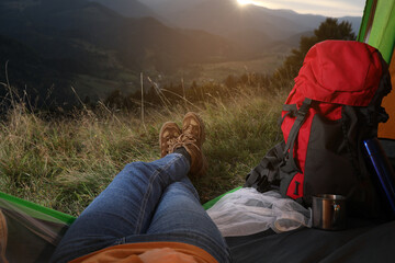 Fototapeta premium Woman resting inside of camping tent in mountains at sunset, closeup