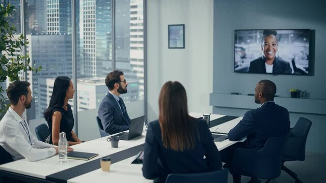 Video Conference Call in Office Meeting Room: Black Female Executive Talks with Group of Multi-Ethnic Digital Entrepreneurs, Managers, Investors. Businesspeople Discuss e-Commerce Investment Strategy