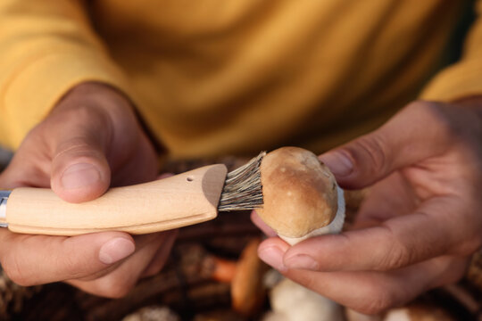 Man Cleaning Mushroom With Brush On Knife, Closeup