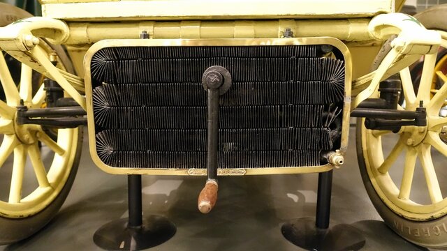 a view of a radiator and a crank of an antique car 