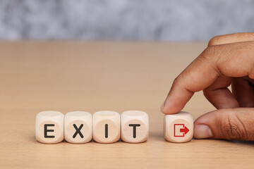 Wooden cube with text EXIT on wooden table background.