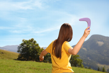 Woman throwing boomerang in mountains, back view. Space for text