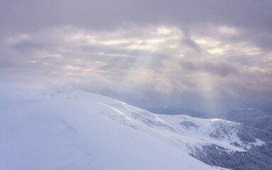 Fototapeta premium Snow covered slopes under a cloudy sky.