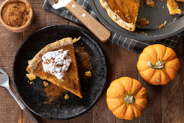 Slice of pumpkin pie with whipped cream and cinnamon