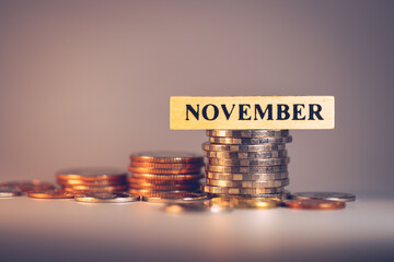 November wooden block on stack coins using as business banking, stock exchange and financial concept