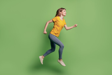 Fototapeta na wymiar Profile portrait of funny inspired active lady jump run wear yellow t-shirt jeans sneakers on green background