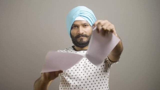 Frustrated angry sikh man tearing and throwing papers by looking camera - conept Job loss, debt or eviction notice and contract failure.