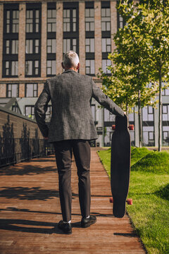 A Mature Man With A Skateboard In The Office District