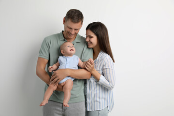 Fototapeta premium Portrait of happy family with their cute baby on white background