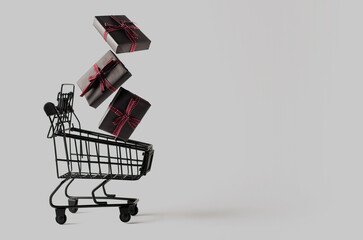 Black toy shopping cart with three levitating gift boxes on gray background with copy space.