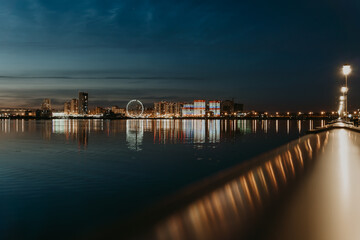 Fototapeta na wymiar City night lights. Kazan embankment. New residential complexes. Reflection on the surface of the water. Long-term exposure.