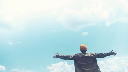 Copy space of man rising hands on blue sky white clouds abstract background. Freedom feel good and...