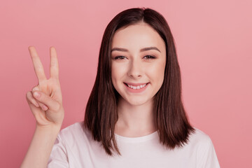 Photo of young attractive woman happy positive smile show cool peace v-sign isolated over pink color background