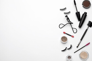Composition with eyelash curler and makeup products on white background, top view