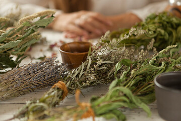  bunch of dried medicinal herbs in women's hands, a collection of medicinal herbs, a white wooden table